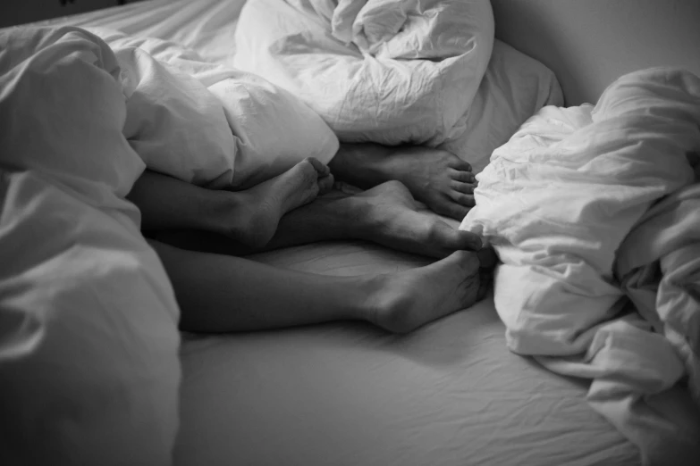 a black and white photo of a person laying in bed, by Matija Jama, pexels, figuration libre, legs intertwined, couple, early morning, getty images