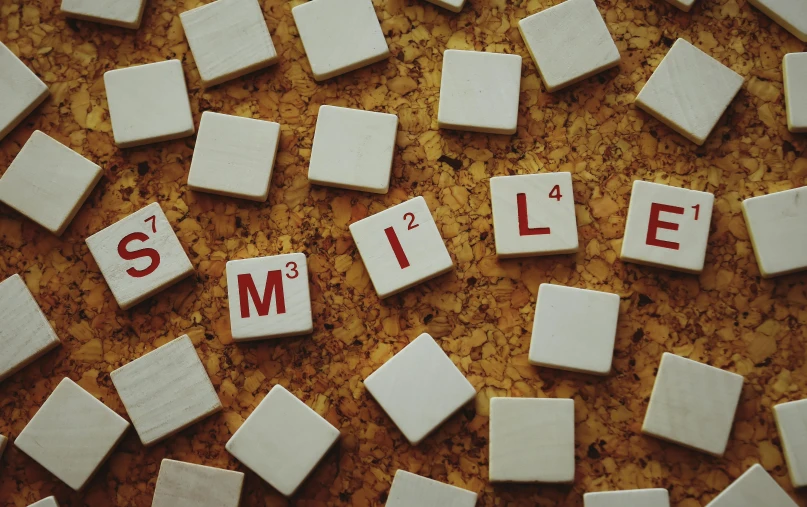 the word smile spelled in scrabbles on a cork board, by Emma Andijewska, pexels contest winner, letterism, tiles, profile pic, all teeth, mills