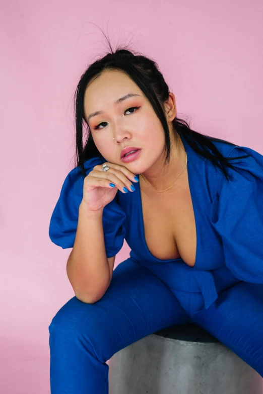 a woman in a blue jumpsuit sitting on a stool, an album cover, inspired by helen huang, instagram, open v chest clothes, profile image, bbwchan, asian female