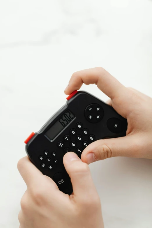 a person holding a remote control in their hand, red - black, tactile buttons and lights, holding scale, thumbnail