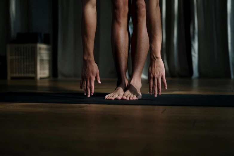 a close up of a person standing on a yoga mat, pexels contest winner, male and female, two arms and to legs, thumbnail, low lighting