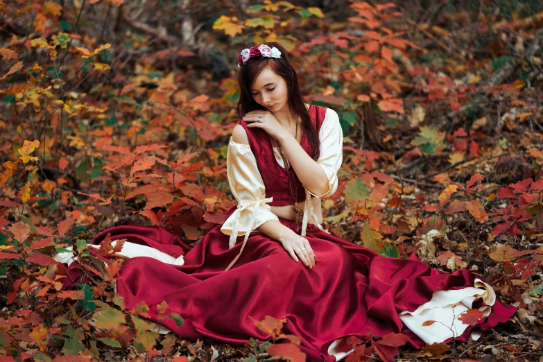 a woman sitting on the ground in a red dress, a photo, by Julia Pishtar, trending on pixabay, renaissance, foliage clothing, maroon and white, dressed with long fluent clothes, 15081959 21121991 01012000 4k