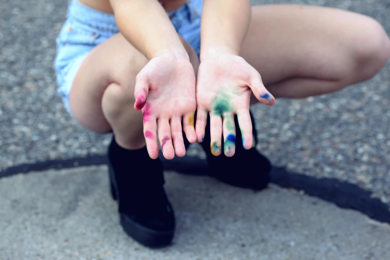 a woman sitting on the ground with her hands painted, trending on pexels, multicolor, teenage, hands down, stains