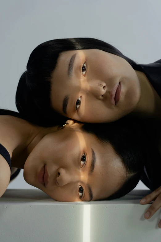 a couple of women standing next to each other, an album cover, inspired by Wang Duo, trending on pexels, hyperrealism, asian face, they are all laying down, symmetrical pupils, non binary model