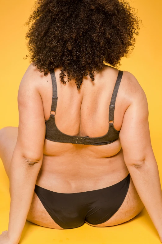 a woman in a bikini sitting on the floor, trending on pexels, morbidly obese, showing her shoulder from back, on a yellow canva, curvaceous. detailed expression