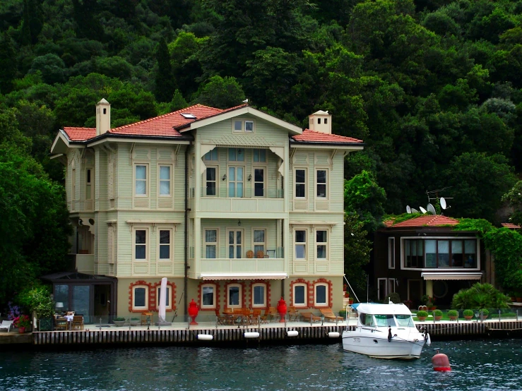a house on the water with a boat in front of it, inspired by Niyazi Selimoglu, pexels contest winner, hurufiyya, an elegant green, 1910s architecture, square, bay