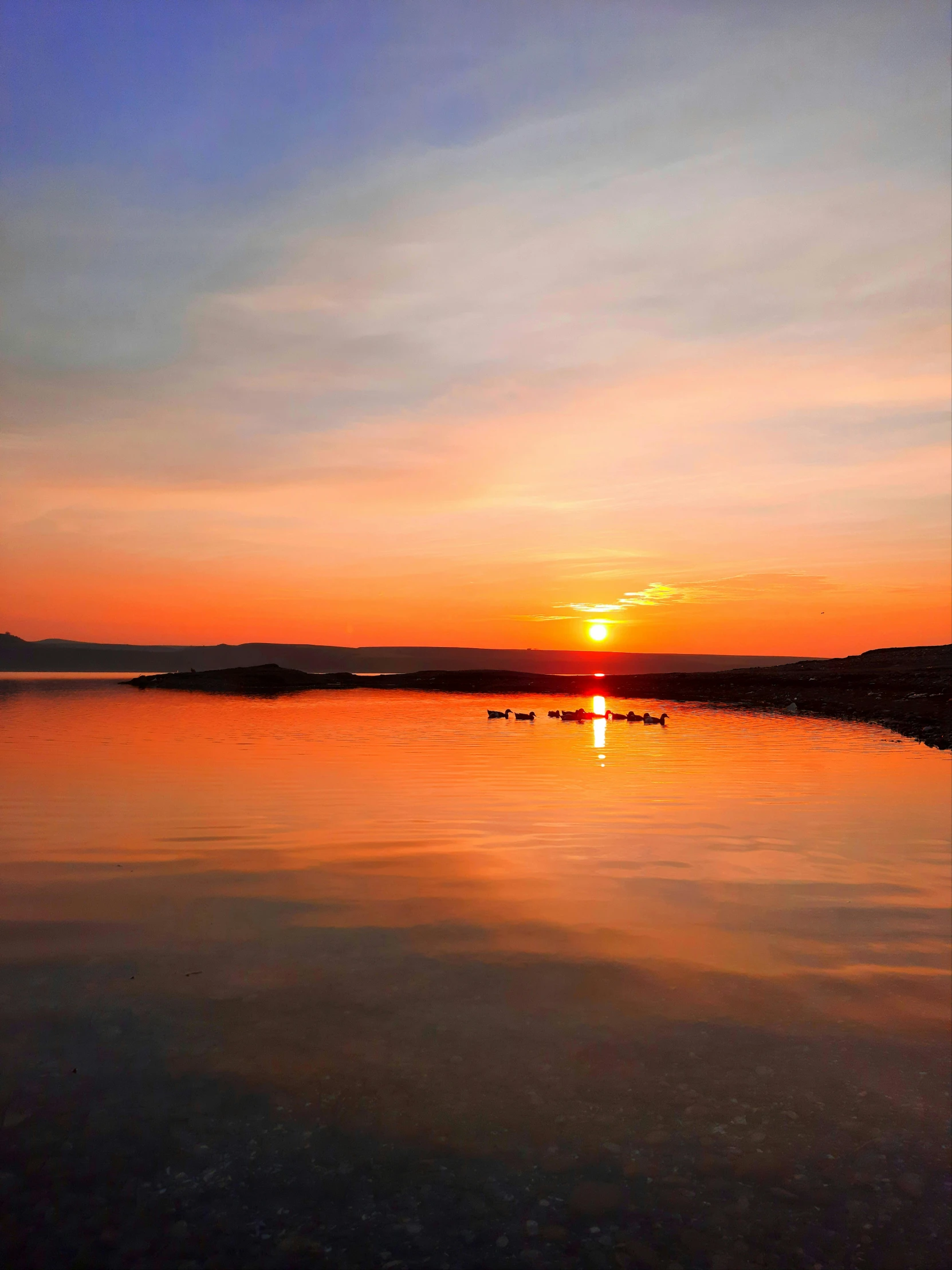 the sun is setting over a body of water, by Muggur, pexels contest winner, calm environment, hamar, low quality photo, photo on iphone