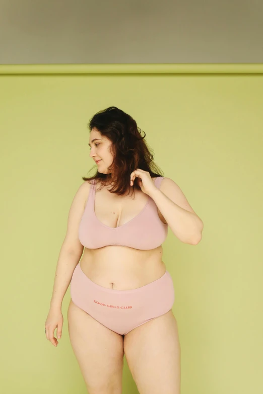 a woman in a pink bikini standing in front of a green wall, by Anita Malfatti, unsplash, happening, plus-sized, on a pale background, posing together in bra, pastel pink