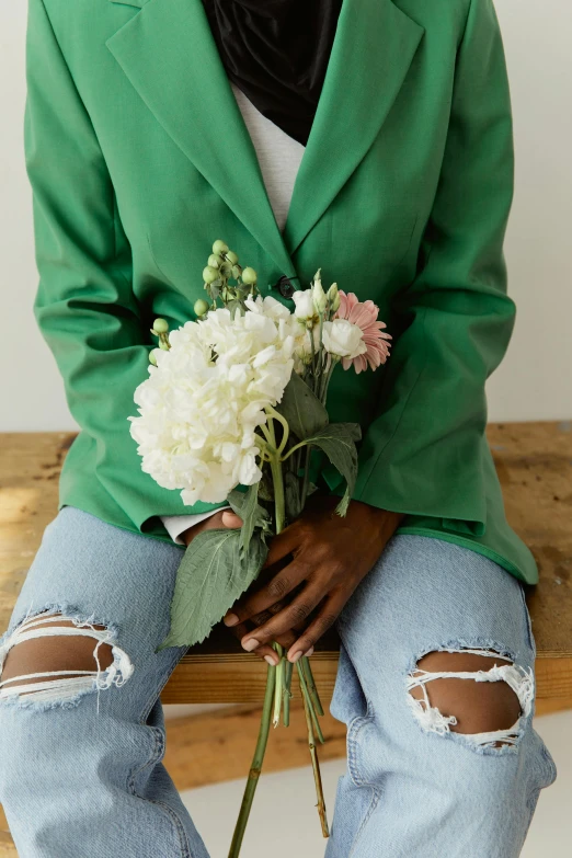 a woman sitting on a bench holding a bouquet of flowers, inspired by François Boquet, trending on unsplash, wearing green jacket, dark skin tone, on a white table, subject detail: wearing a suit