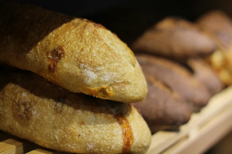 a bunch of bread sitting on top of a wooden shelf, slide show, lit from the side, crispy buns, woodfired