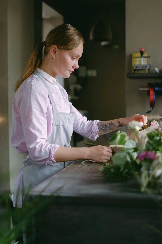 a woman that is standing in front of a counter, holding a flower, filleting technique, skilled, minna sundberg