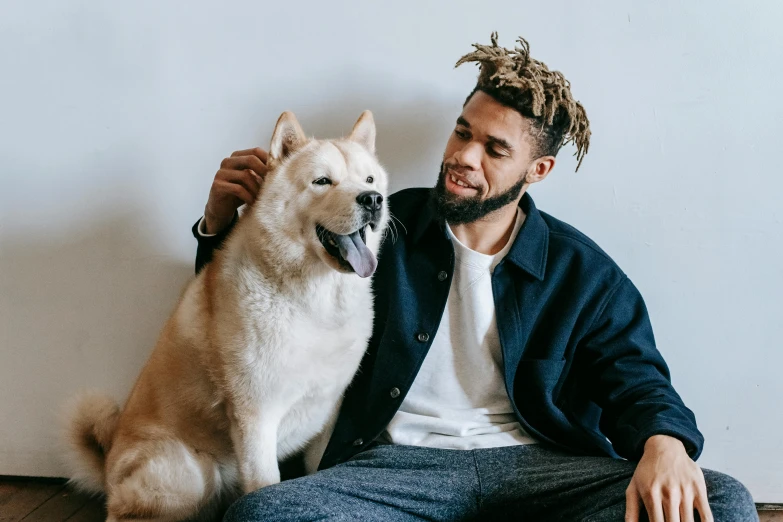 a man sitting on the floor with his dog, trending on pexels, brown skin man with a giant grin, wearing spiky, profile image, 2 animals