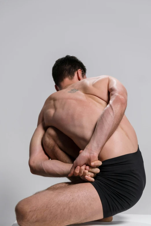 a man sitting on a stool with his back to the camera, inspired by Fei Danxu, depressed dramatic bicep pose, wrestling, square, padmasana