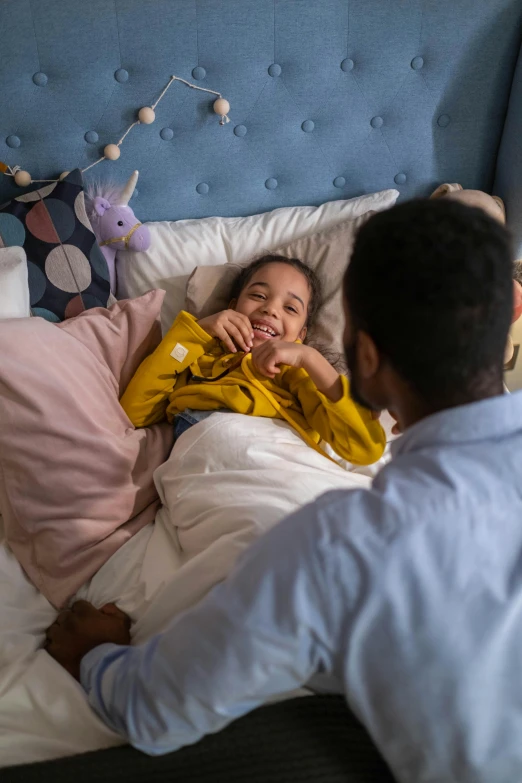 a man and a little girl laying in a bed, a stock photo, pexels contest winner, healthcare, supportive, amber, behind the scenes