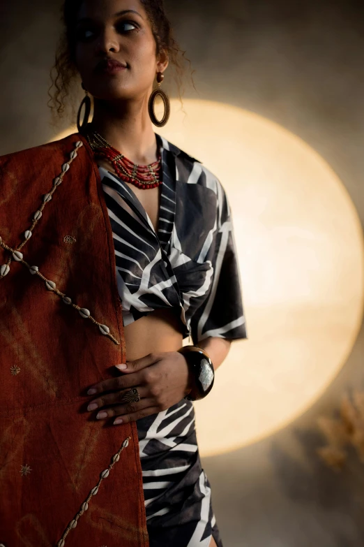 a woman standing in front of a full moon, afrofuturism, bracelets and necklaces, red silk flowing fabric, curated collections, indian style