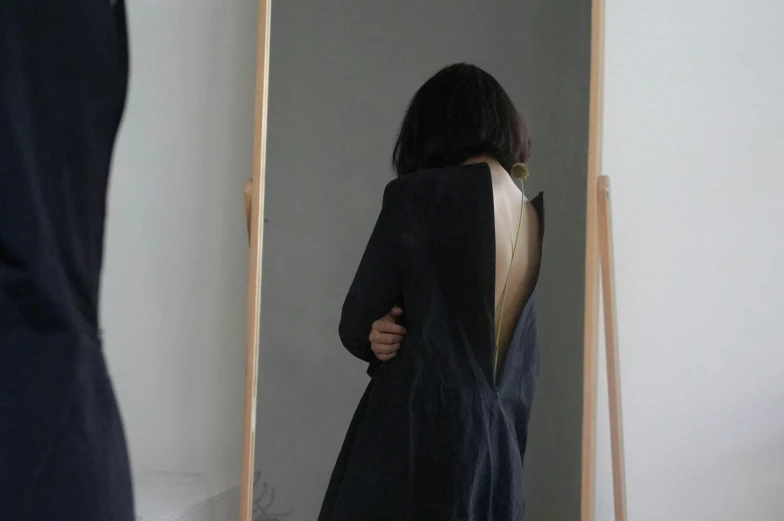 a woman standing in front of a mirror, pexels contest winner, arte povera, open back dress, wearing a black jacket, heonhwa choe, ignant