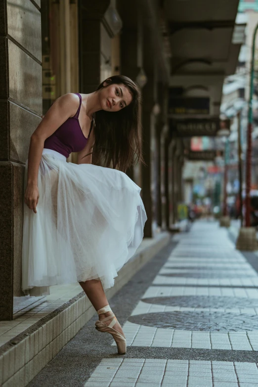 a woman that is standing in the street, arabesque, wearing purple romantic tutu, wearing white skirt, serious composure, square