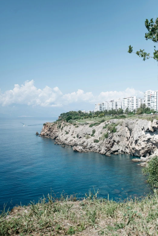 a bench sitting on the side of a cliff next to a body of water, black sea, lush surroundings, surrounding the city, sloped site
