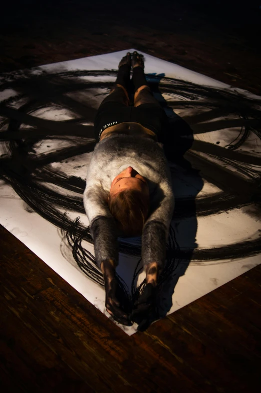 a dog laying on top of a white sheet of paper, a charcoal drawing, inspired by Hans Hartung, unsplash, body painted with black fluid, shibari, spinning hands and feet, she is laying on her back