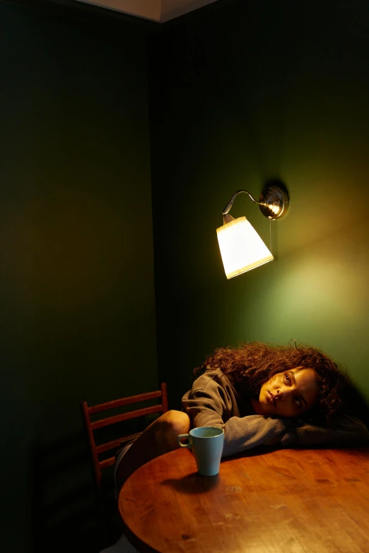 a woman sitting at a table with a cup of coffee, inspired by Nan Goldin, diffuse overhead lighting, sleeping, imaan hammam, ( ( photograph ) )