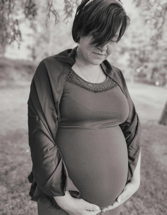 a black and white photo of a pregnant woman, by Terese Nielsen, pexels contest winner, happening, dressed in a gray, slightly smiling, outdoor photo, colour corrected