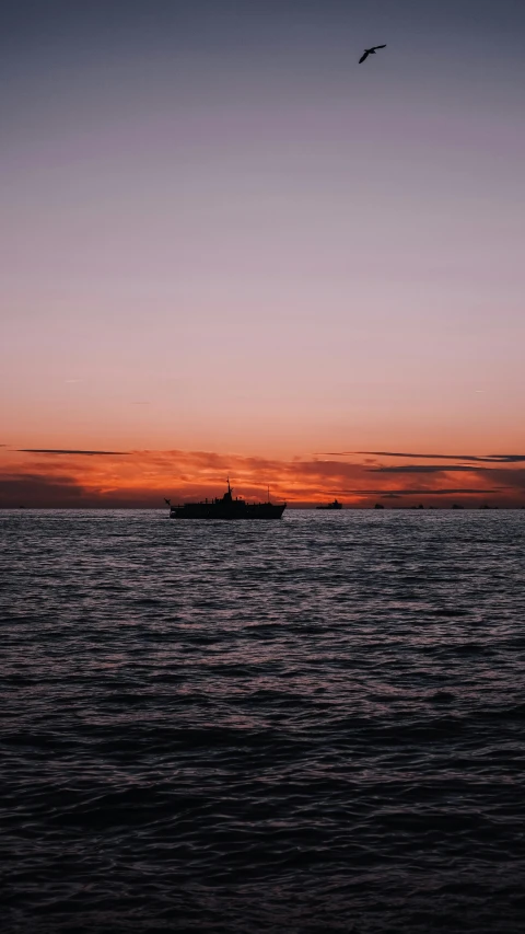 a large body of water with a boat in the distance, by Robbie Trevino, unsplash contest winner, sunsetting color, shipfleet on the horizon, low quality photo, film photo