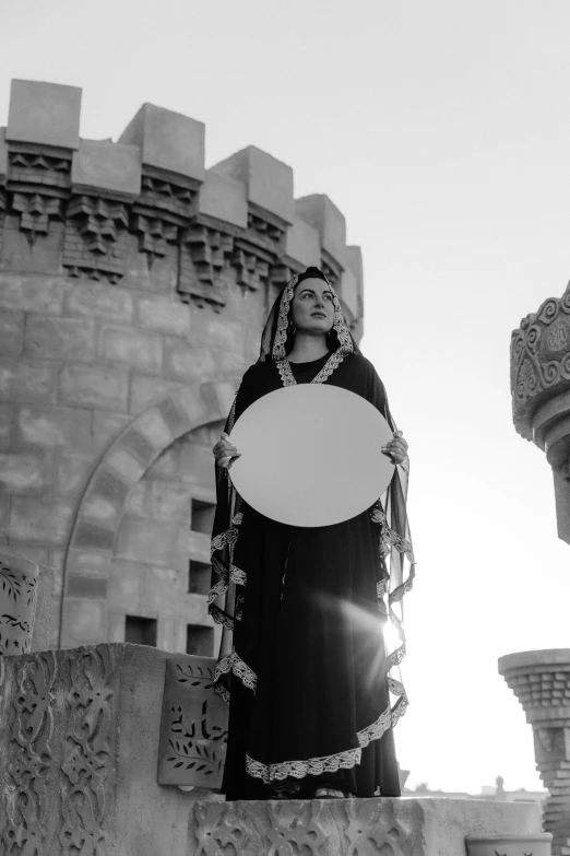 a statue of a woman standing in front of a castle, a black and white photo, inspired by Claude Cahun, symbolism, holding khopesh and shield, publicity cosplay, in a major mesopotamian city, dressed in a [ [ 1 2 th century