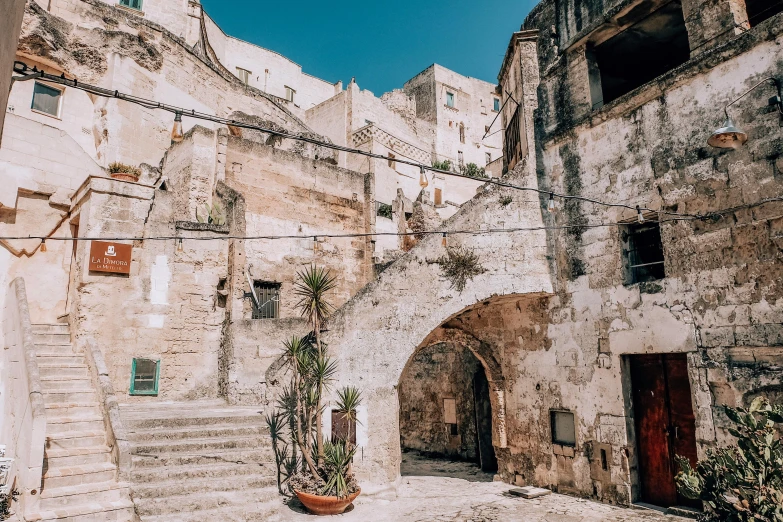 a stone building with a potted plant in front of it, an album cover, by Julia Pishtar, pexels contest winner, mingei, stairs and arches, apulia, shady alleys, city view