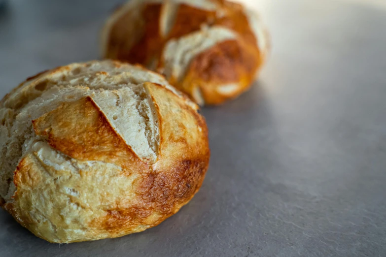 a couple of breads sitting on top of a table, with a round face, up close, detailed product image, good light