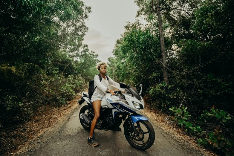 a woman riding on the back of a motorcycle down a road, pexels contest winner, in a tropical forest, portrait willow smith, full body pose, sydney park