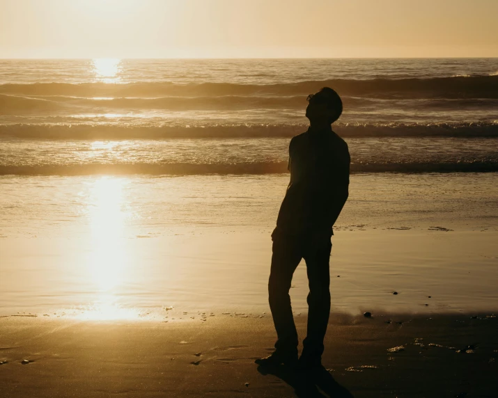 a man standing on top of a beach next to the ocean, pexels contest winner, full body backlight, profile image, pondering, outlined silhouettes