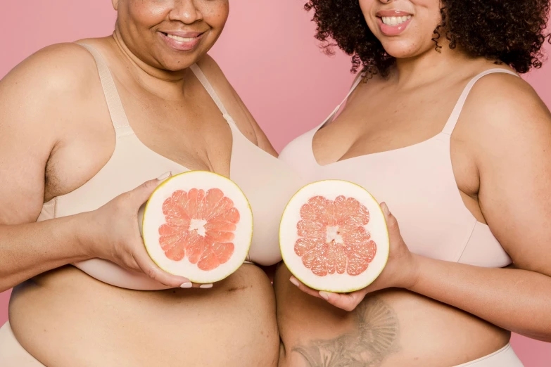 a couple of women standing next to each other holding grapefruits, by Arabella Rankin, trending on pexels, figuration libre, covered in pink flesh, posing together in bra, plus-sized, wearing shipibo tattoos