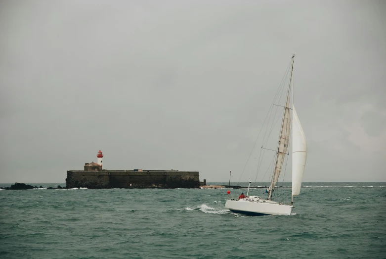 a sailboat in the ocean with a lighthouse in the background, pexels contest winner, figuration libre, martin parr, grey, port city, la nouvelle vague