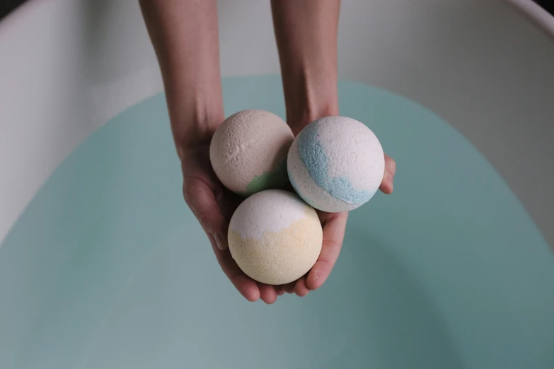 a person holding three bath bombs in their hands, a still life, unsplash, natural colours, angled shot, chalky, 3/4 front view