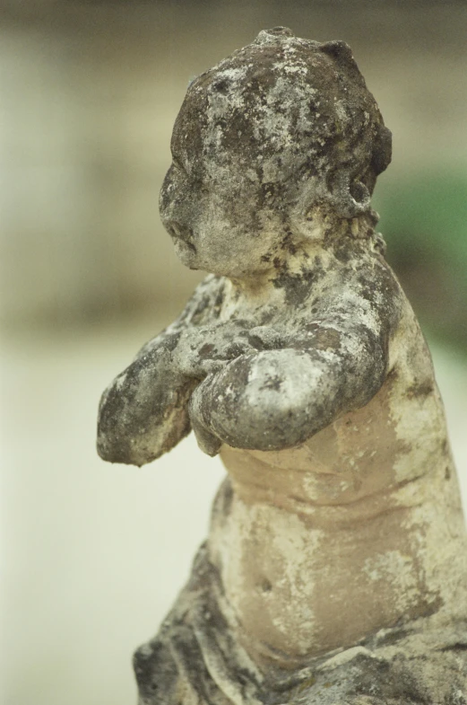 a close up of a statue of a child, photographed on colour film, intricate body, lush surroundings, limestone