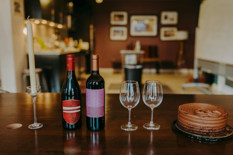 a couple of wine bottles sitting on top of a wooden table, dessert, red and black colour scheme, at the counter, amanda lilleston