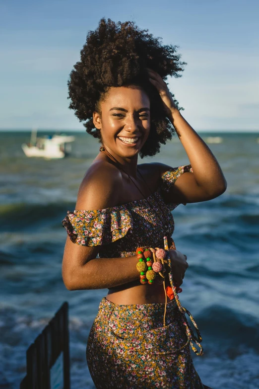 a woman standing in front of a body of water, by Ella Guru, pexels contest winner, dark short curly hair smiling, brazilan supermodel, patterned clothing, ( brown skin )