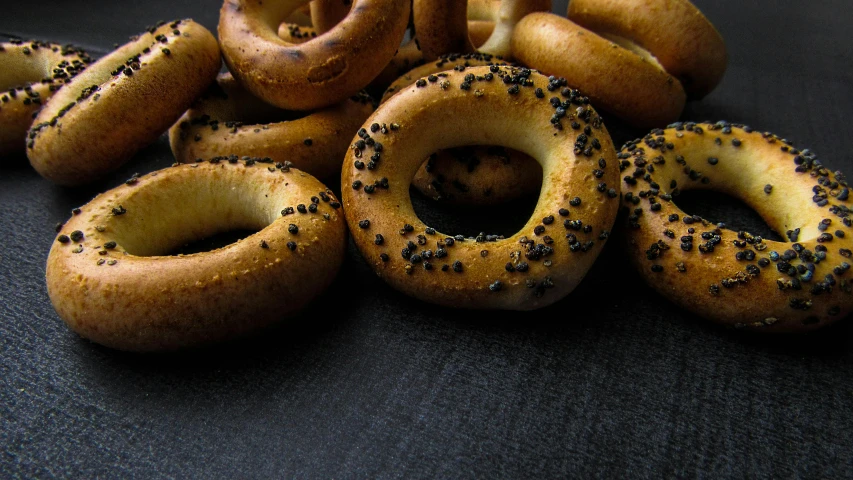 a pile of bagels sitting on top of a table, trending on pexels, hurufiyya, black jewellery, background image, smoky, blender donut