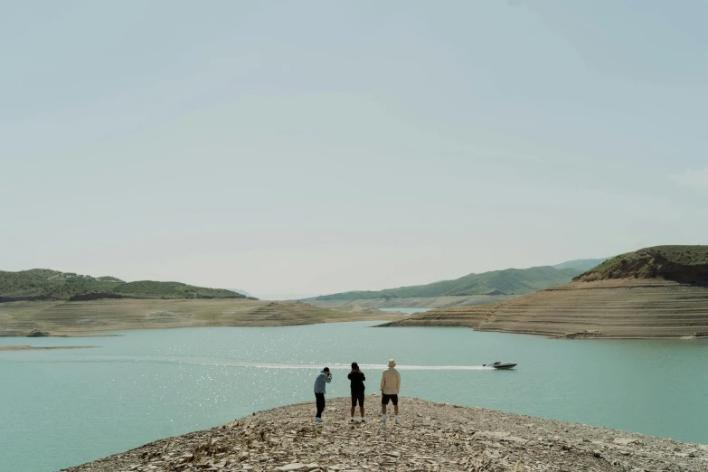 a group of people standing next to a body of water, by Muggur, pexels contest winner, hurufiyya, still from l'estate, water reservoir, three views, nekro petros afshar