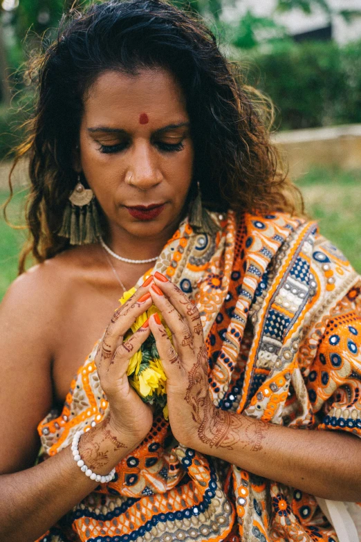 a woman is putting henna on her hands, an album cover, trending on unsplash, renaissance, the non-binary deity of spring, sri lanka, profile image, 3 5 year brazilian mother