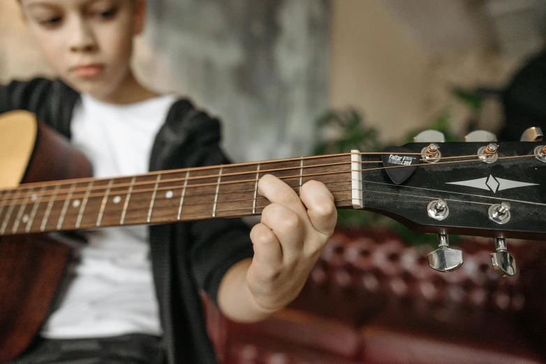 a close up of a person playing a guitar, for junior, modelling, looking across the shoulder, no cropping