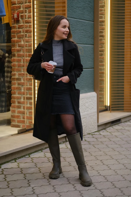 a woman standing on a sidewalk talking on a cell phone, by Niko Henrichon, pexels contest winner, renaissance, over-knee boots, lady in black coat and pantyhose, high-waist-black-skirt, attractive woman