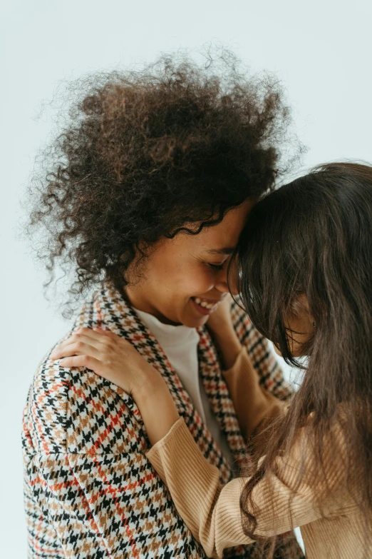 a couple of young girls standing next to each other, trending on pexels, romanticism, mixed race, sweet hugs, brown clothes, curls