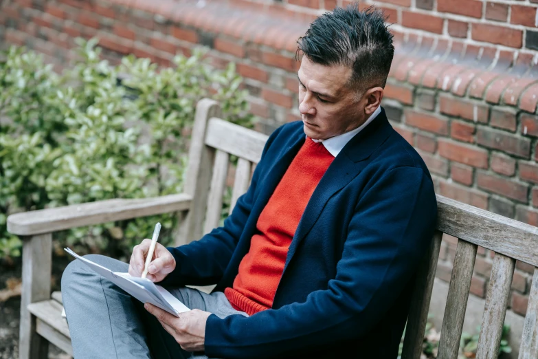 a man sitting on a bench writing on a piece of paper, academic art, wearing red jacket, school curriculum expert, owen gent, tailored clothing