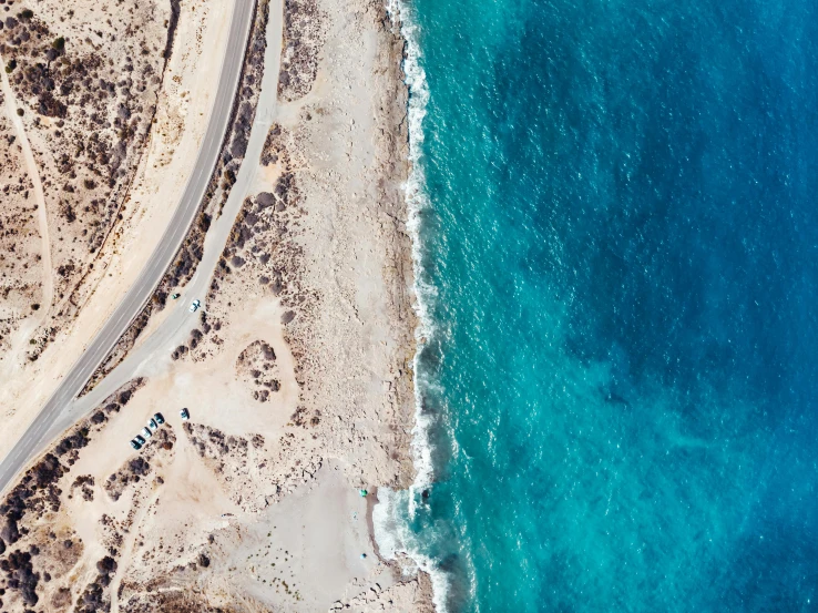 an aerial view of a road next to the ocean, by Lee Loughridge, trending on unsplash, cyprus, azure water, dessert, half and half