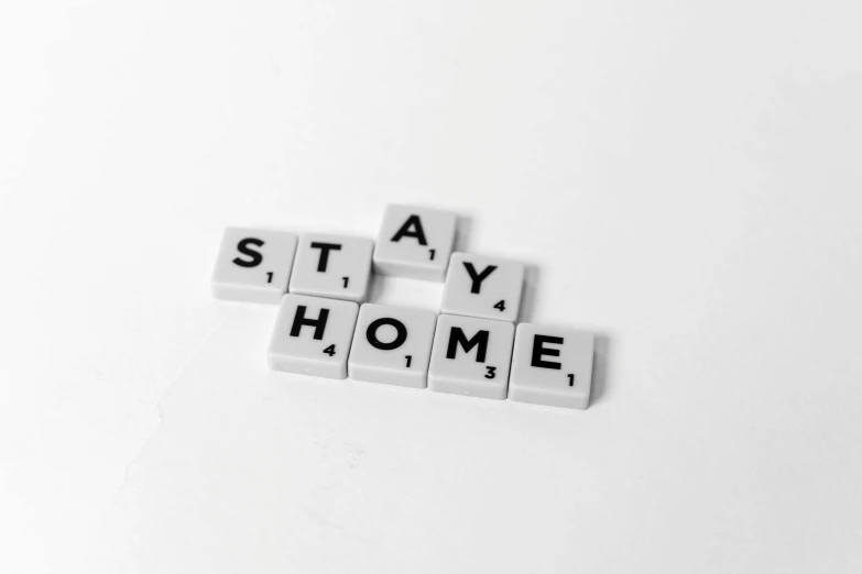 the word stay home spelled in scrabbles on a white surface, a black and white photo, by Matija Jama, pixabay, art-house aesthetic, background image, key still, no bricks
