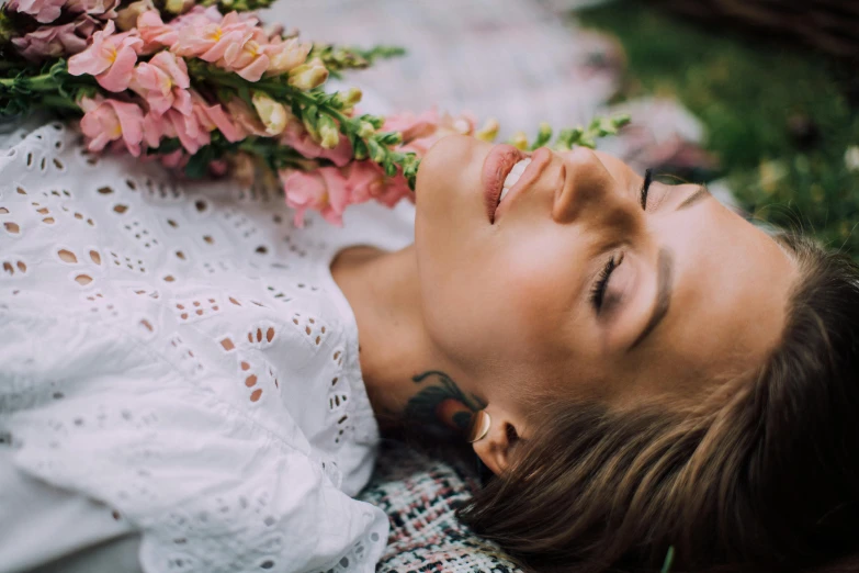 a woman laying on a blanket with flowers in her hair, trending on pexels, attractive photo, lush plants and flowers, a beautiful woman in white, dreaming of kissing a girl