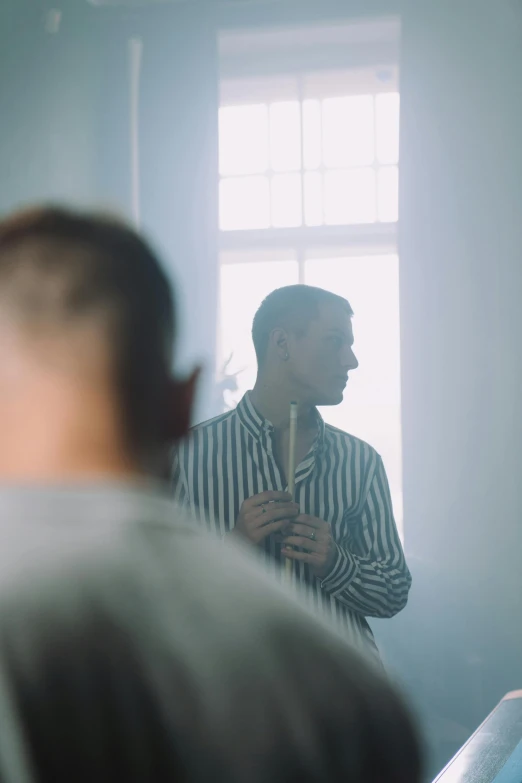 a man standing in front of a mirror in a room, inspired by Oskar Lüthy, pexels contest winner, wearing stripe shirt, light haze, in church, ( ( theatrical ) )