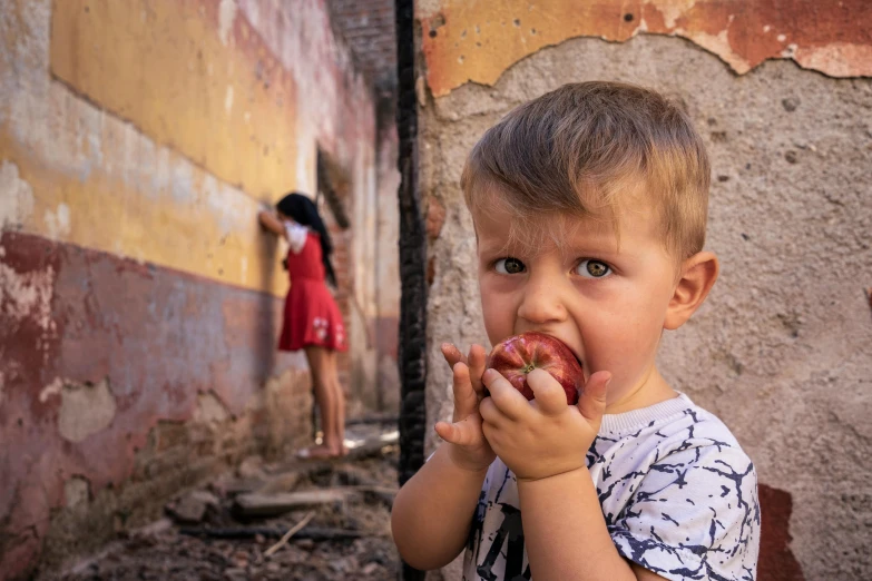 a young boy eating an apple in front of a building, by Lucia Peka, pexels contest winner, ukrainian, eyballs in the walls, 15081959 21121991 01012000 4k, looking threatening