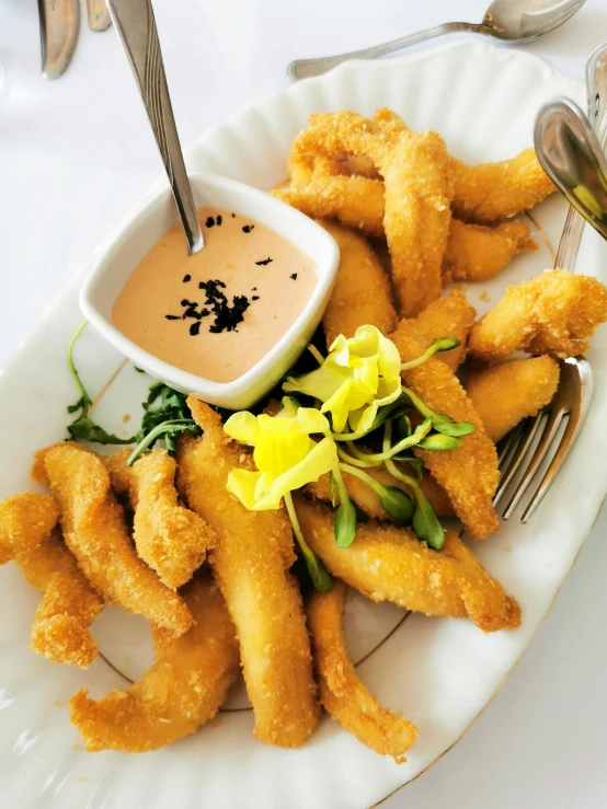 a white plate topped with fried shrimp next to a bowl of dipping sauce, inspired by Pia Fries, unsplash, art nouveau, lillies, new zealand, white spiral horns, 🌸 🌼 💮